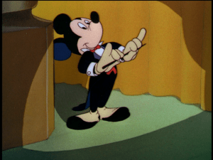 Mickey takes the stage as the announcer begins the broadcast of the "Symphony Hour"
